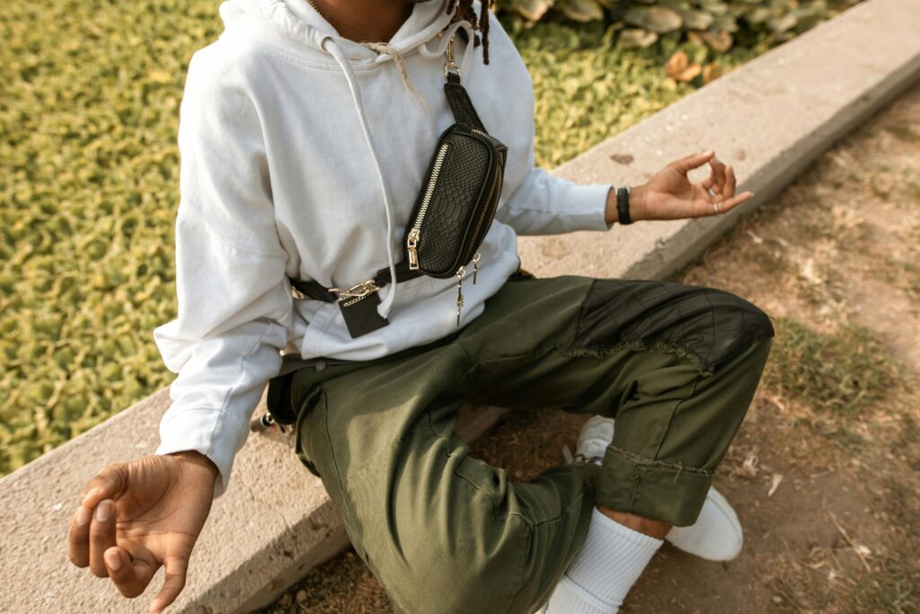 Young adult meditating outdoors in casual attire, focusing on relaxation and mindfulness.