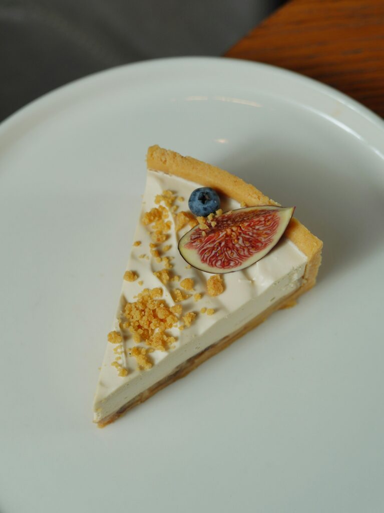 A scrumptious slice of fruit tart with fig and blueberry on a white plate.